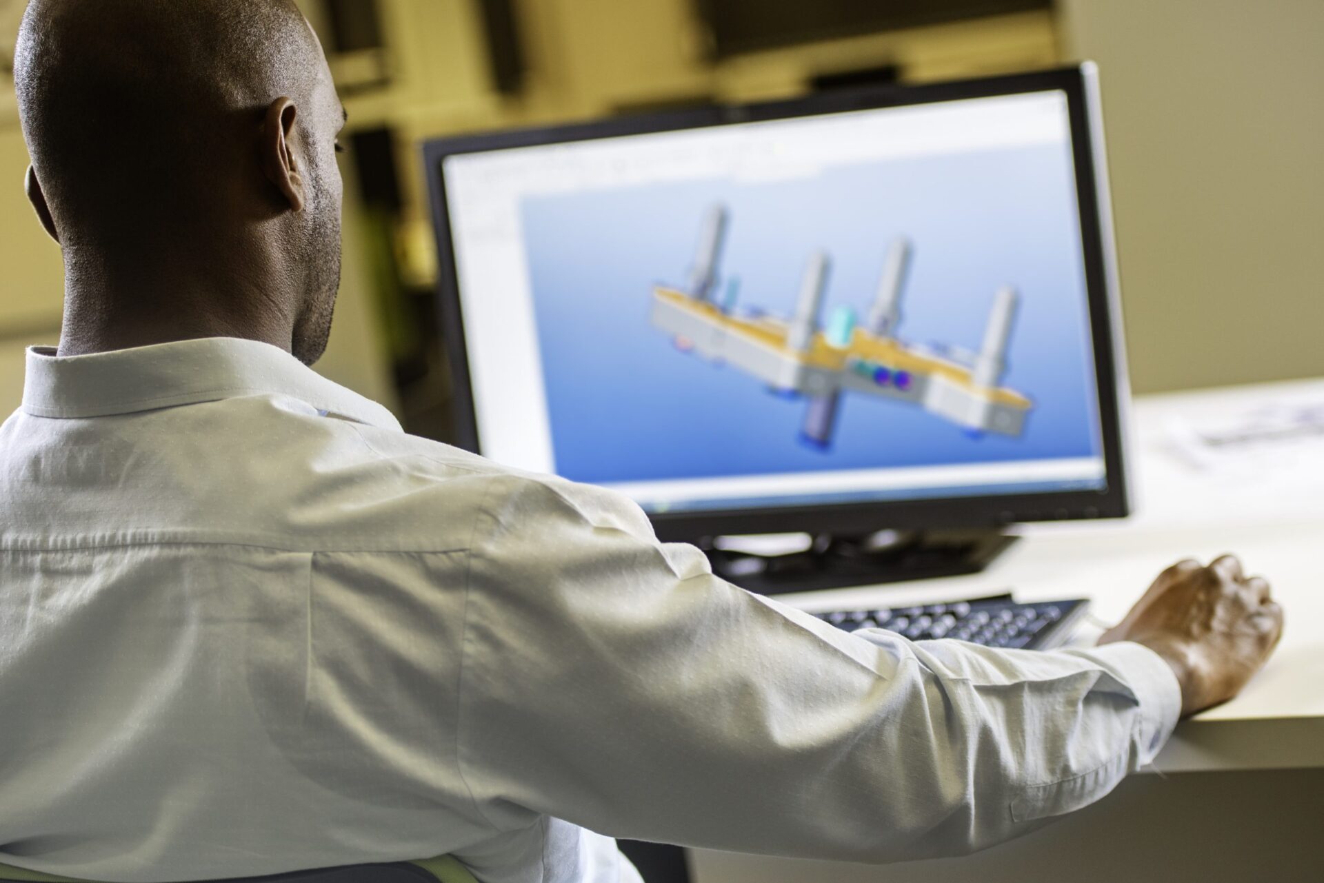 An engineer working on a CAD model of machine structure.