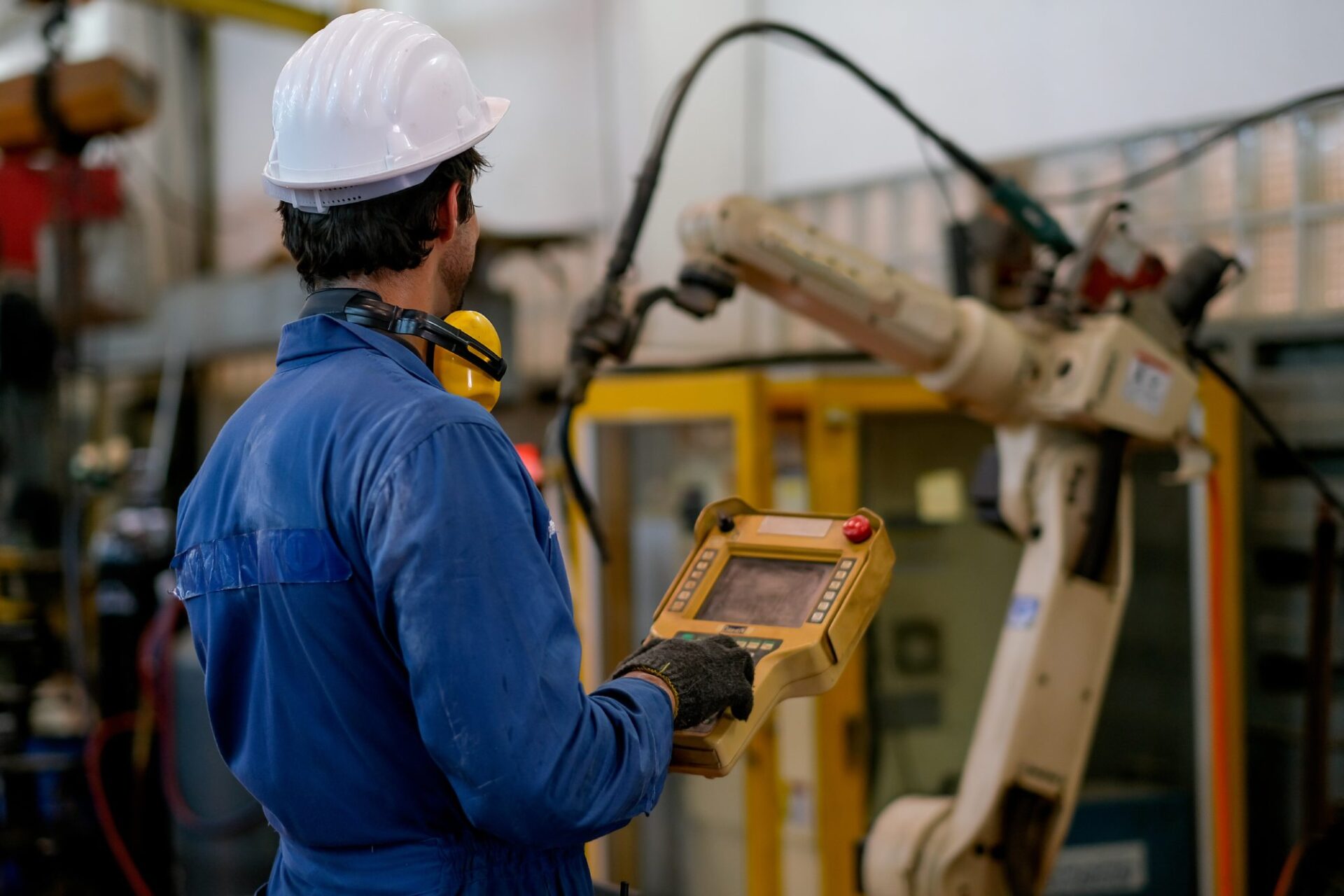 A technician controlling a robot arm in a factory setting