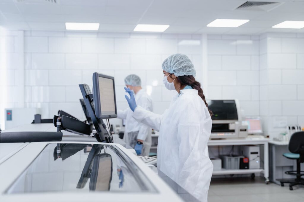 A woman in a white lab coat and mask in a lab environment
