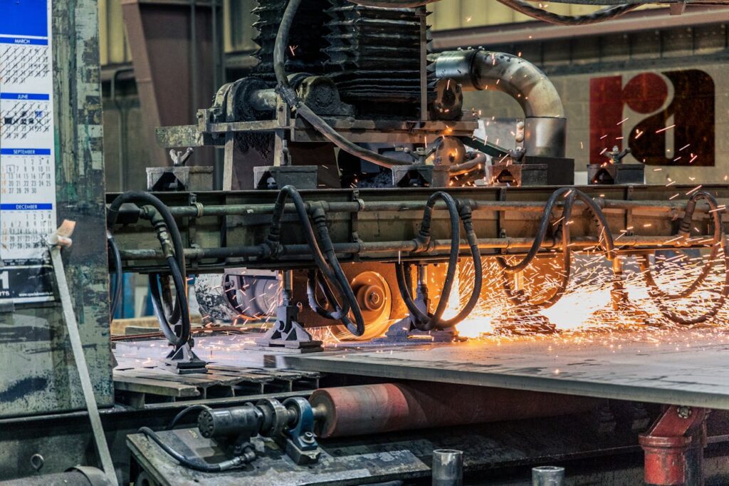 Industrial cutting machine producing bright sparks while slicing through a metal sheet.
