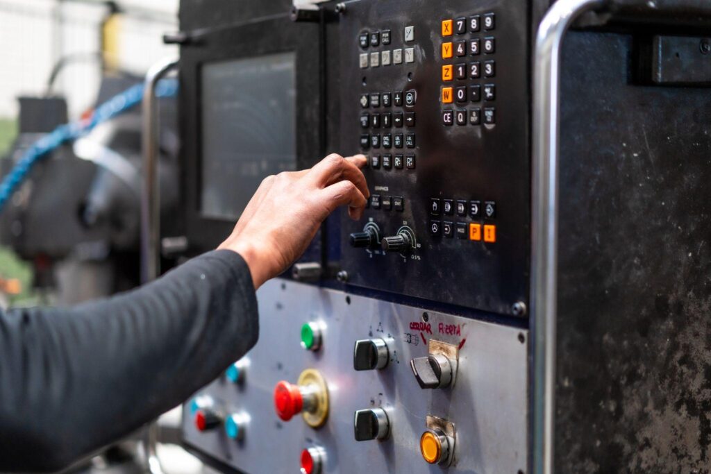 An operator using a control panel attached to industrial machinery