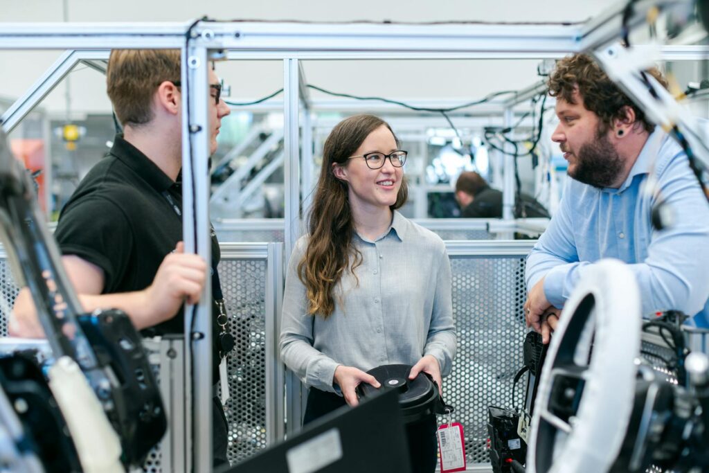 Three engineers discussing equipment inside an industrial automation workspace