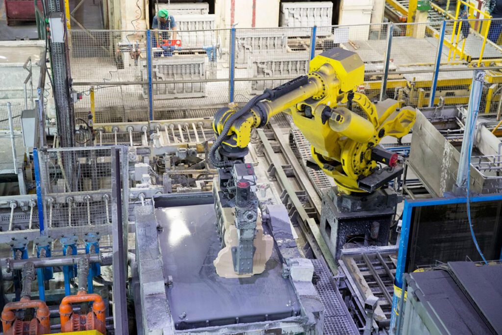 Industrial robotic arm handling molded construction material in an automated manufacturing line.