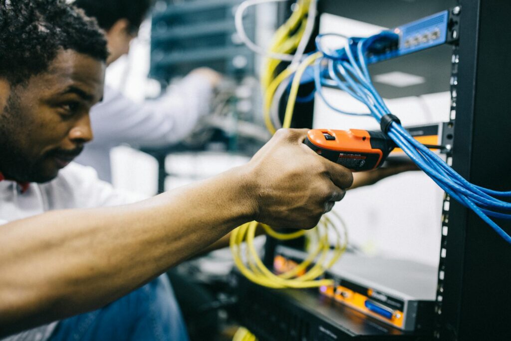 Technician connecting network cables in a server rack with a cable tester